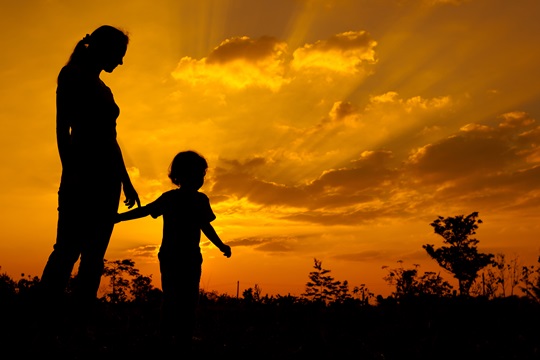 silhouette of a mother and son who play outdoors at sunset background