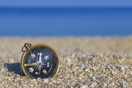 Old compass on the beach with sand and sea